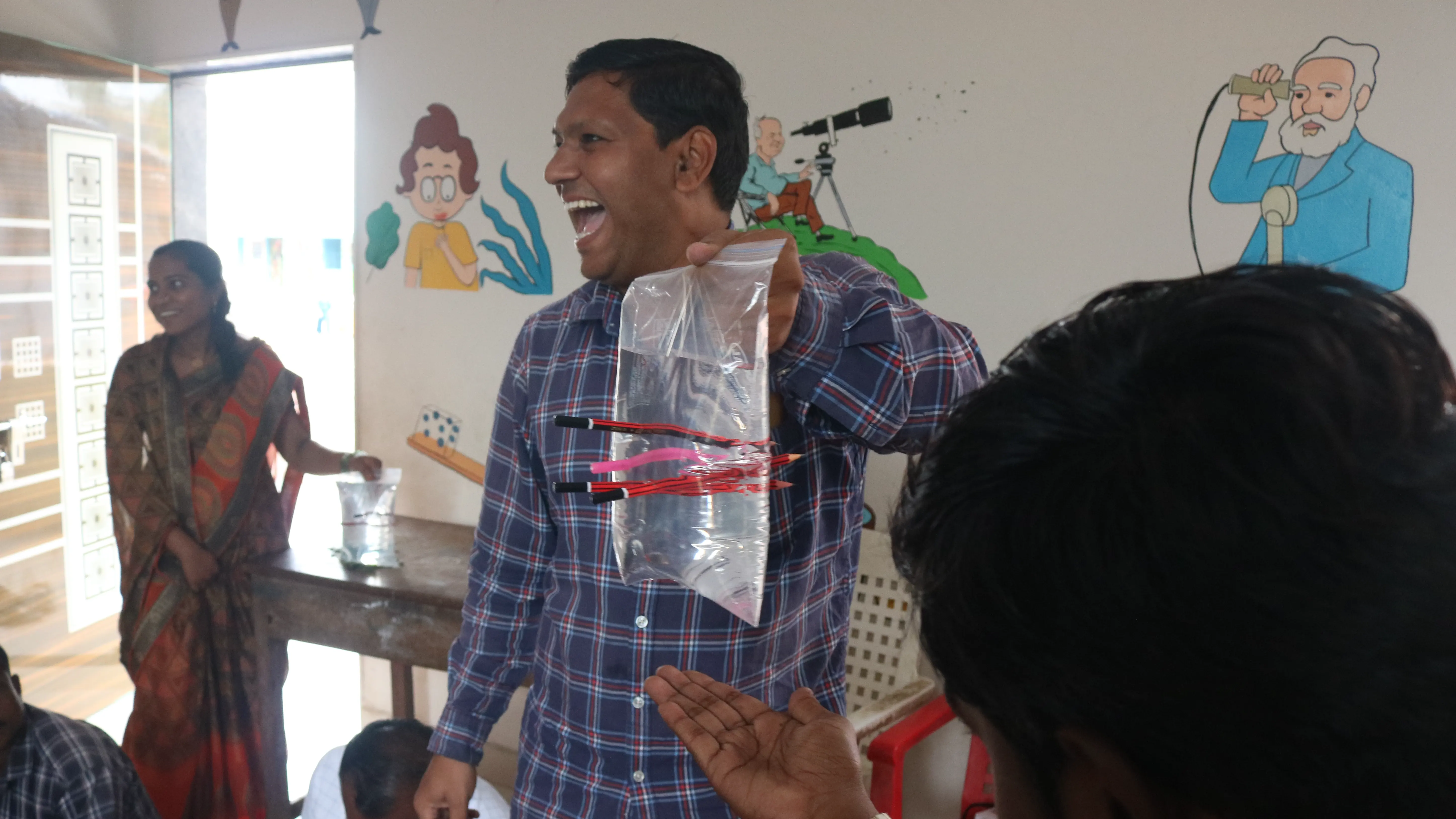 A demo of a plastic bag filled with water with pencils poked through it